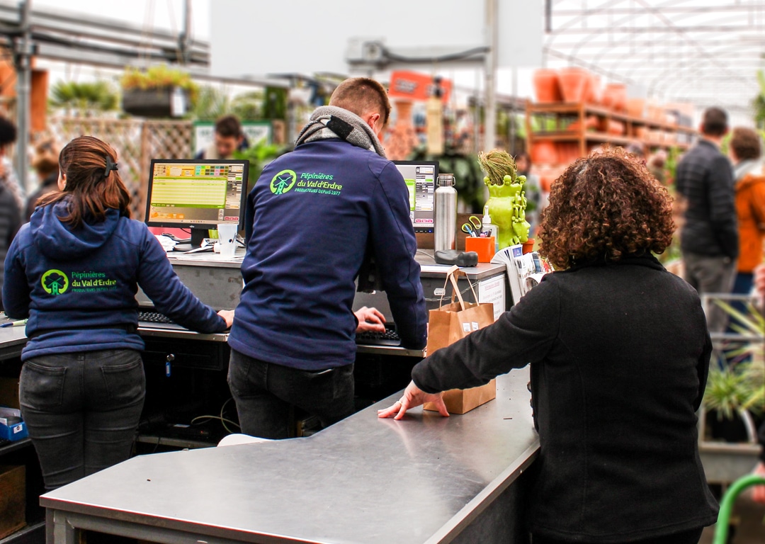 Employés jardineries enregistrent achats clients.